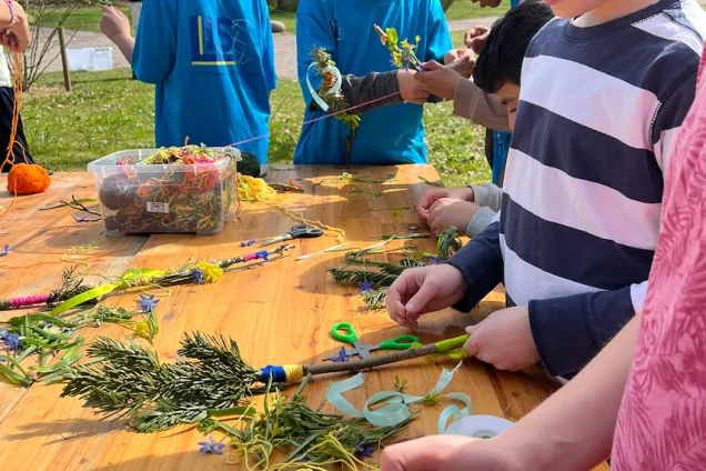 Barn gör trollspön av pinnar, garn och blommor