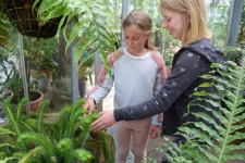 två flickor känner på ormbunksväxter